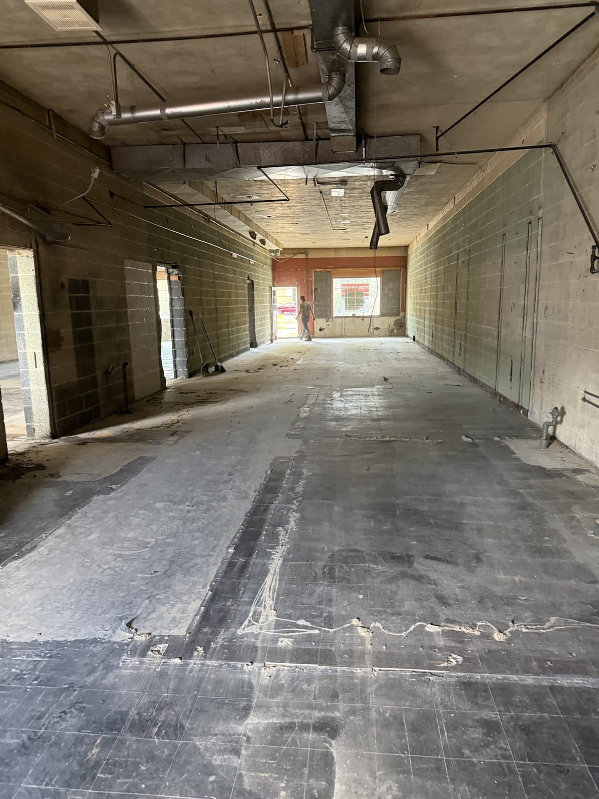 The same building's interior stripped to bare block walls, exposed ductwork, and a concrete slab.